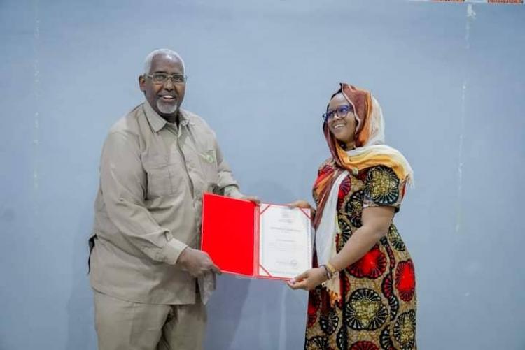 Rector, Prof. Muhamed Muhamud Hassan Biday (left) of Benadir University presents Hellen Muringi (right) from the University of Nairobi with a certificate of appreciation